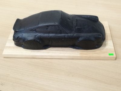 un gâteau noir orné d'une voiture, posé sur une planche en bois