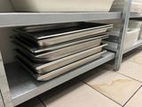 several pans are stacked on top of a metal shelf in a kitchen