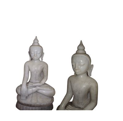 deux statues de bouddhas assis sur une surface blanche