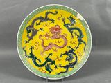 assiette jaune et verte ornée de motifs de dragons, posée sur un socle