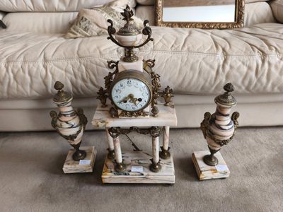 une horloge et trois vases posés par terre devant un canapé