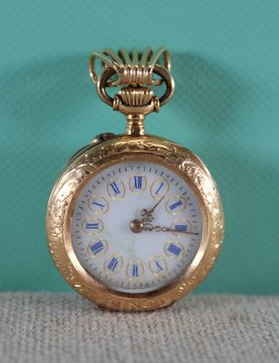 a gold pocket watch sitting on a table with a green background