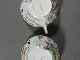 two cups with floral designs on them are sitting on a table