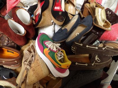 a pile of shoes and purses on a bed
