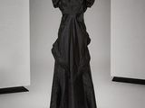une photo d'une robe noire posée sur un présentoir à mannequin dans une pièce