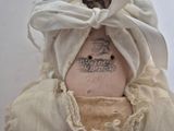 a close up of a doll wearing a white dress and a white hat