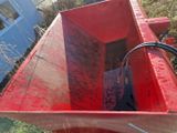 une benne rouge posée dans l'herbe à côté d'un bâtiment bleu