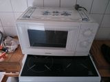 un micro-ondes posé sur une cuisinière dans une cuisine