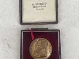 an image of a gold medal in a case with a red ribbon