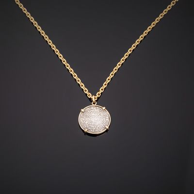 un collier en or avec une pièce de monnaie sur une chaîne