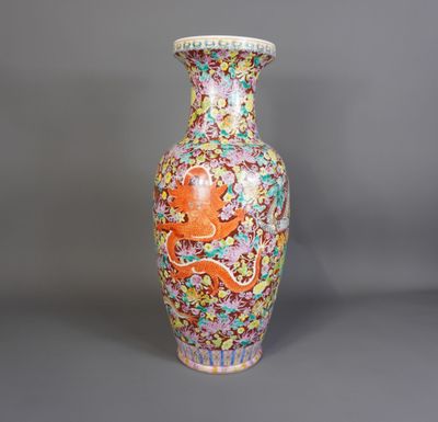 un vase orange et bleu orné d'un dragon, posé sur un fond gris