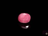 a close up of a pink stone on a black surface