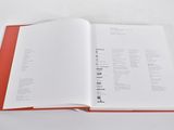 an open book on a white table with a red cover
