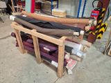 Plusieurs rouleaux de tissu sont empilés sur un support dans un garage.