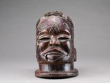 une image représentant un masque en bois orné d'un visage d'homme