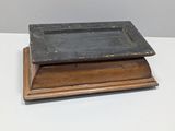 an old wooden tray with a black top sitting on a white surface