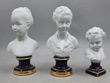 three white porcelain busts of women with black bases and gold trim
