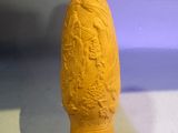 someone is holding a yellow vase in their hand on a white surface