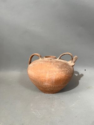 un grand vase marron posé sur une surface grise