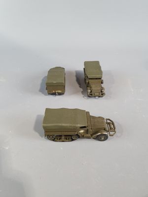 three toy army vehicles sitting on a white surface