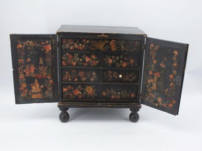 une petite armoire noire ornée d'un motif floral