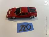 une petite voiture rouge posée sur une table, à côté d'une feuille de papier bleue