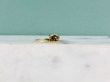 un gros plan d'une bague en or sertie d'un diamant noir, posée sur un bloc de marbre