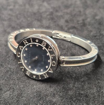 une bague en argent sur laquelle est posée une montre, posée sur une table