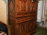 a wooden cabinet in the corner of a room with a suitcase on the floor