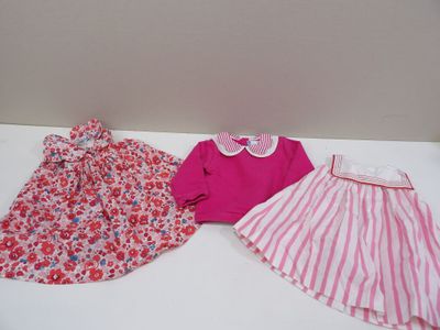 two dresses and a shirt are sitting on a white table
