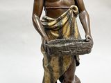 bronze statue of a man holding a basket of fruit next to a lemon