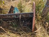 a rusted out boat sitting in the grass