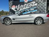 une Mercedes Classe SL argentée garée devant un magasin de voitures anciennes