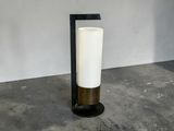 une bougie blanche posée sur un support noir, près d'un mur blanc