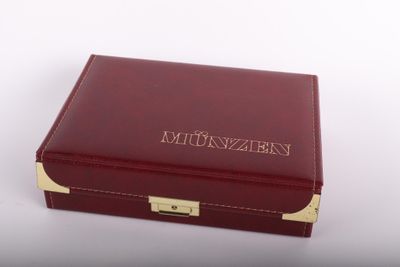 La boîte est rouge, ornée de motifs dorés, et porte un nom.