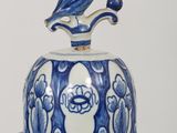 a blue and white vase with a bird on top of it