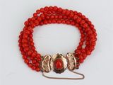 un bracelet en perles rouges avec un fermoir doré