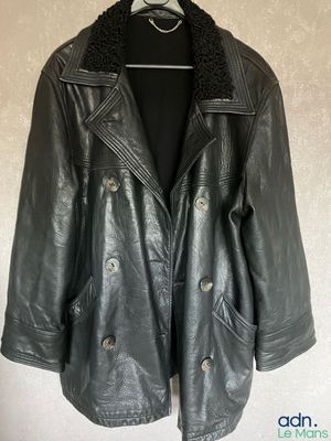 une veste en cuir noir suspendue à un cintre accroché au mur