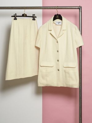 deux vêtements suspendus à un portant devant un mur rose et blanc
