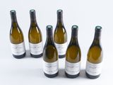 six bottles of wine are lined up in a row on a white surface