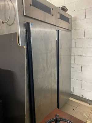 un grand réfrigérateur en acier inoxydable dans une cuisine, à côté d'un mur en briques