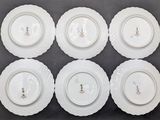 six white plates with designs on them are arranged on a table