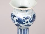 a blue and white vase with a small bowl on top