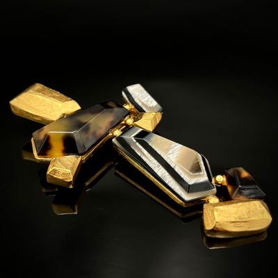 deux bijoux dorés et noirs posés sur une surface noire