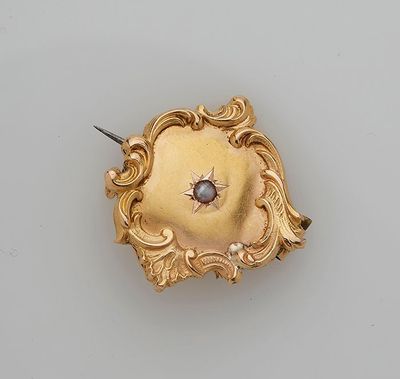 an 18k gold broochle with a blue stone in the center