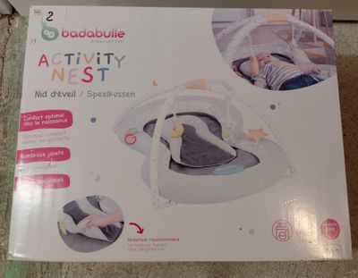 une boîte posée par terre, avec un bébé à l'intérieur