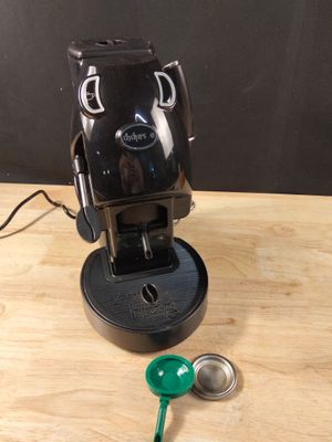 une cafetière noire posée sur une table en bois, avec une clé verte