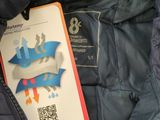 a blue jacket with a tag attached to it that has a picture of a dragon on it