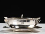un service en argent ancien composé d'un bol et d'une soucoupe, posé sur une table blanche