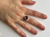 someone is holding a ring with a purple stone on it